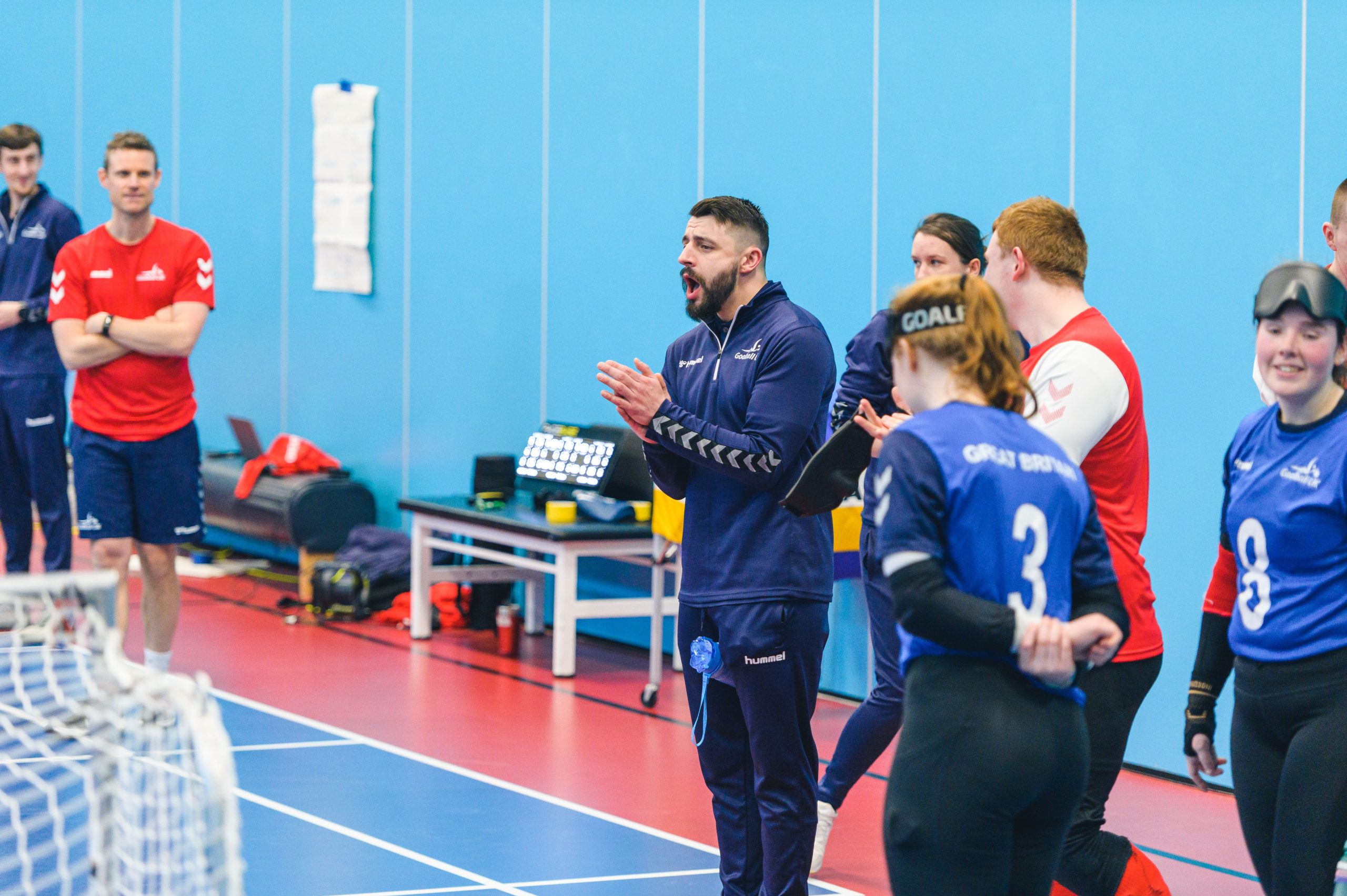During a GB training camp a male coach is shouting and clapping his hands together to encourage players