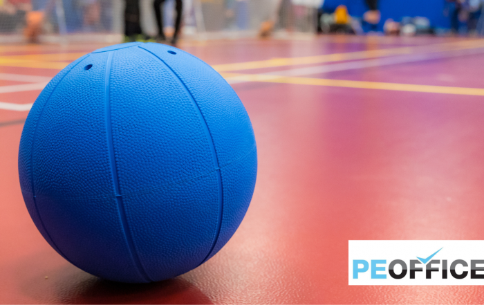 A goalball in focus at the front of the image on a red court that is out of focus behind it. In the bottom left corner is the PE Office logo
