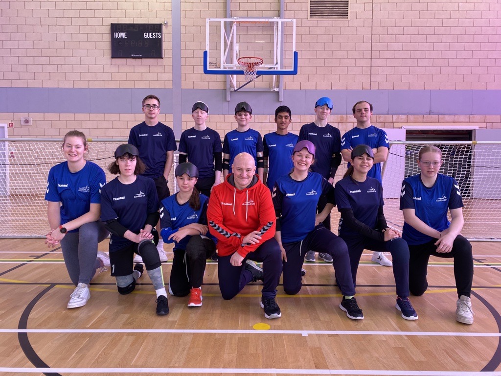 Group image of the Goalball Academy players and coaches. The back row are standing and the front row are kneeling