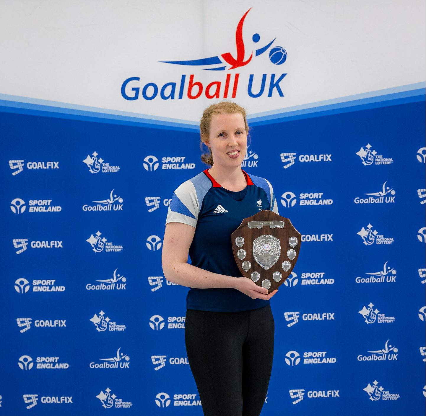 Georgie Bullen with her award in front of a Goalball UK banner.