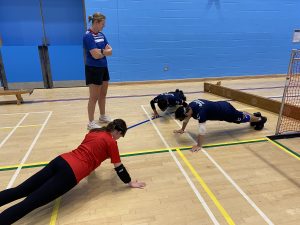 three members of the Goalball Academy are put through their paces with push ups in the warm up hall