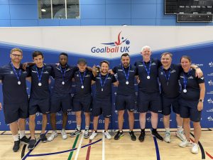 GB Men athletes and coaches pose for a group photo in their blue kit