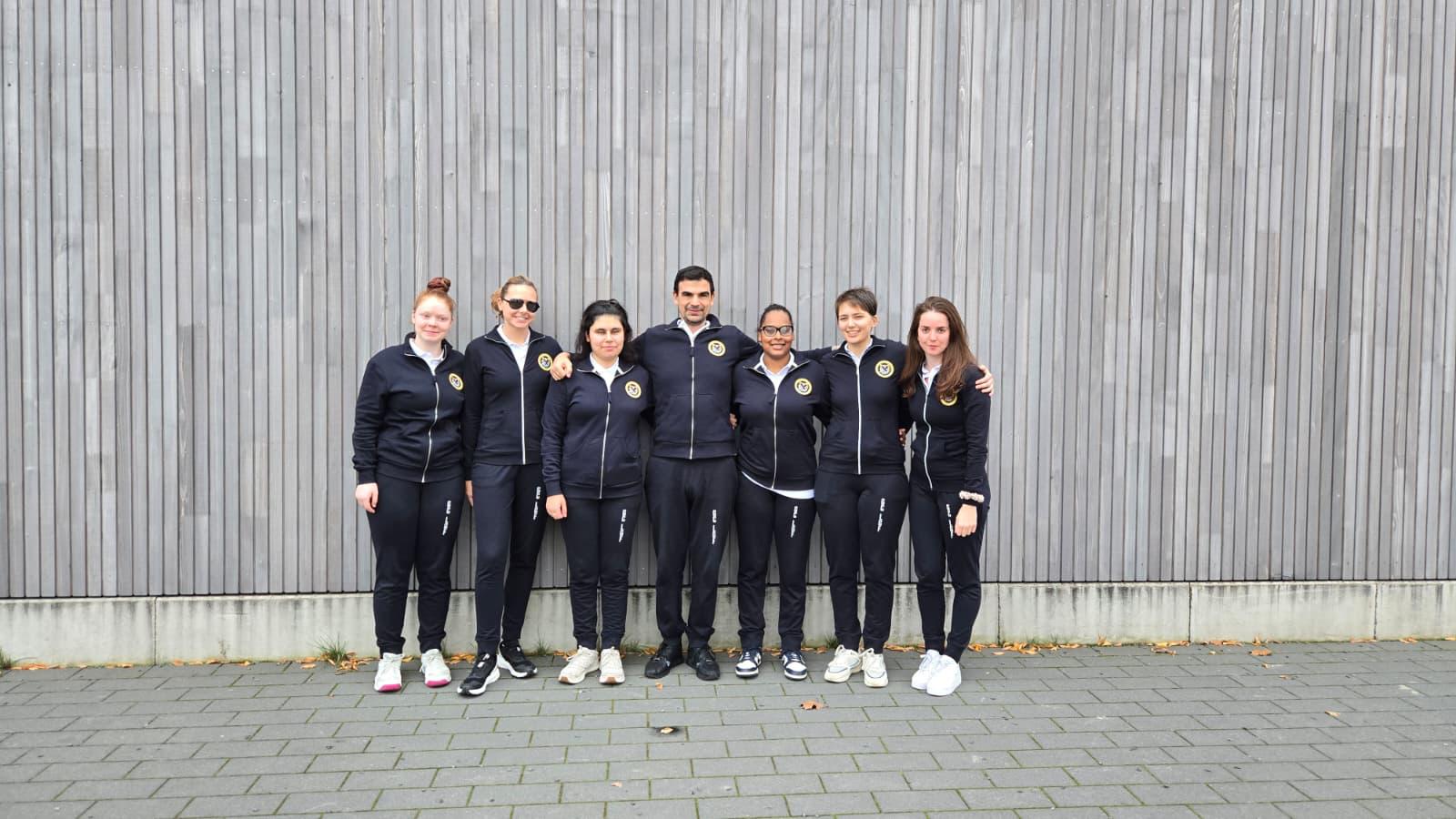 GC Golden Flash squad photo, all 7 team members are standing outside in black tracksuits with their arms around one another.