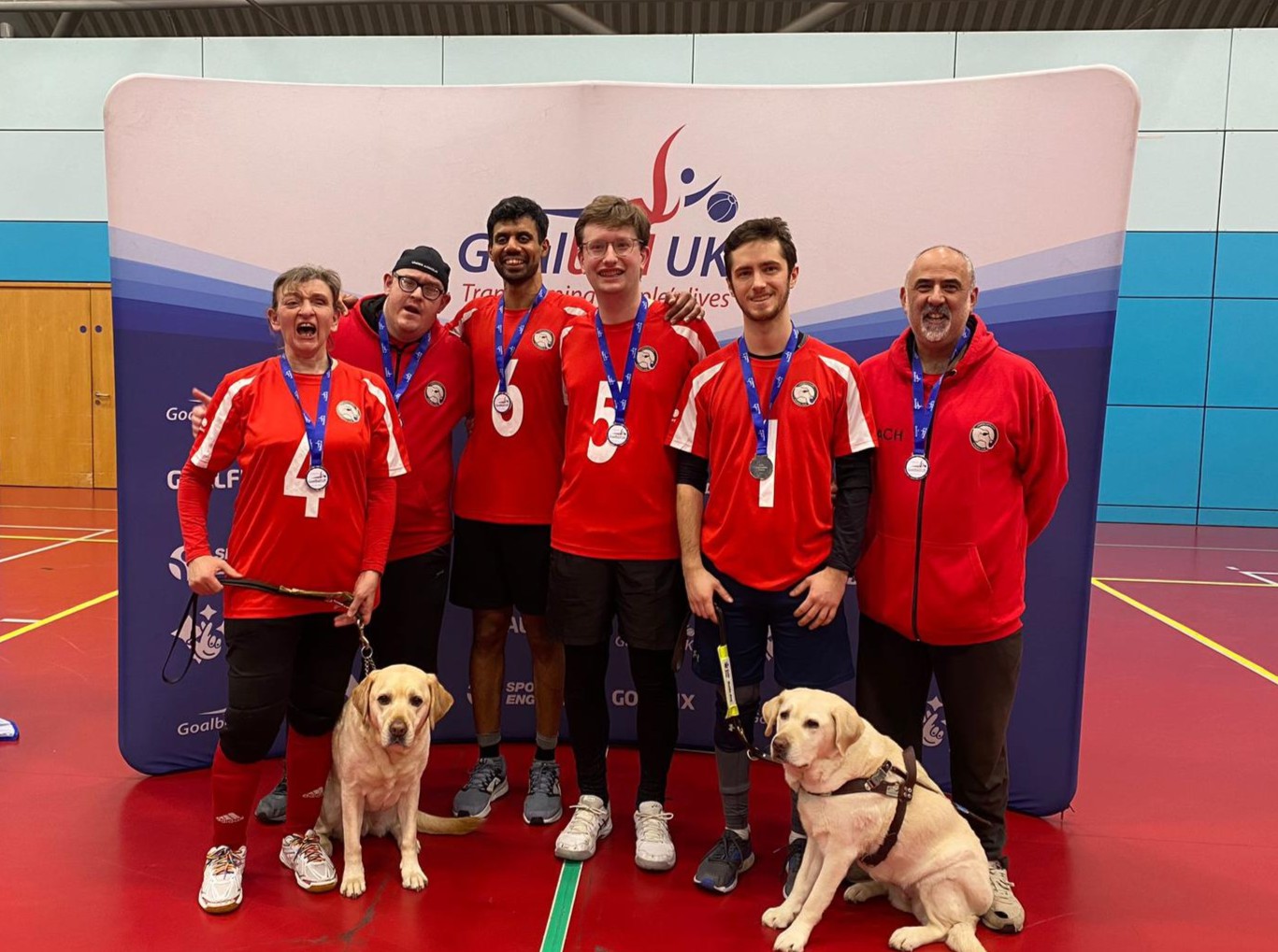A team celebrating with medals. London Elephants group photo, all wearing their red jerseys and receiving a medal.