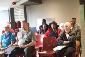 A group of coaches sat in chairs listening to a presentation