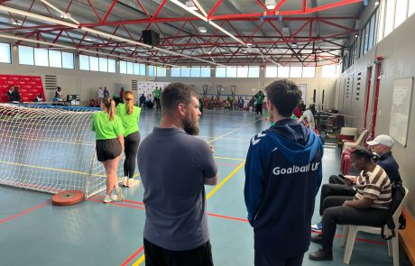 Alex taking to a coach behind the goal in a sports hall.