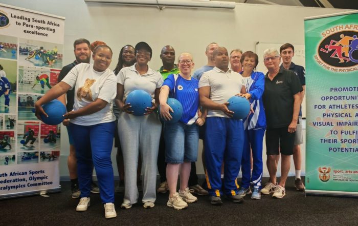 A group stands in front of two banners promoting para-sport in South Africa, including the South African Sports Confederation and Olympic and Paralympics Committee, and messages supporting athletes with physical and visual impairments.