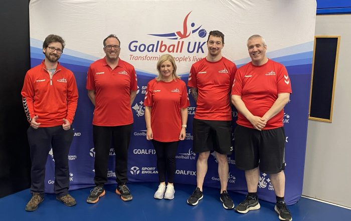 5 newly qualified referees in red tshirts stood in front of a Goalball UK banner