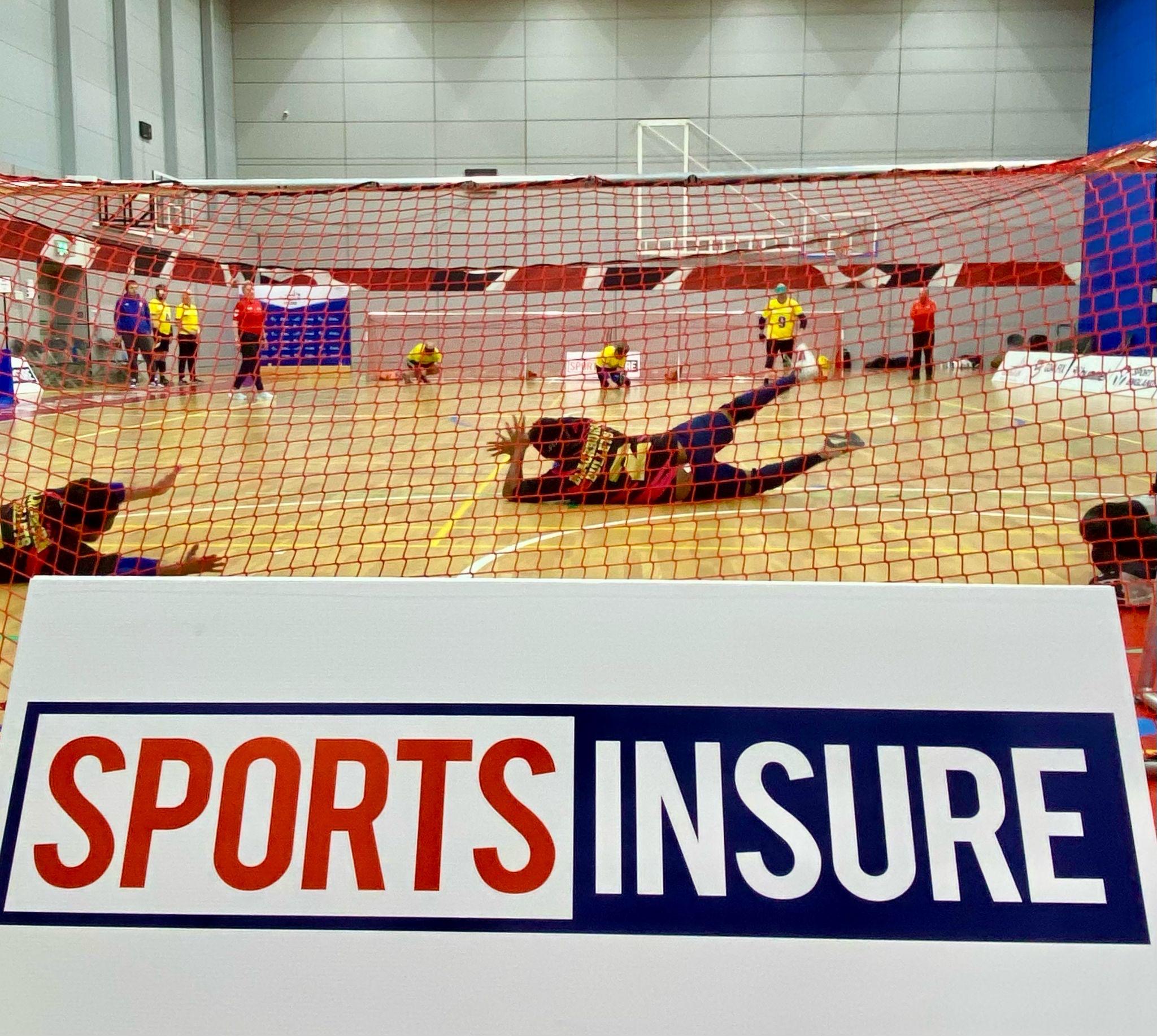 Photo from the last Sports Insure competition from behind the nets. The Sports Insure logo A board is in the foreground.