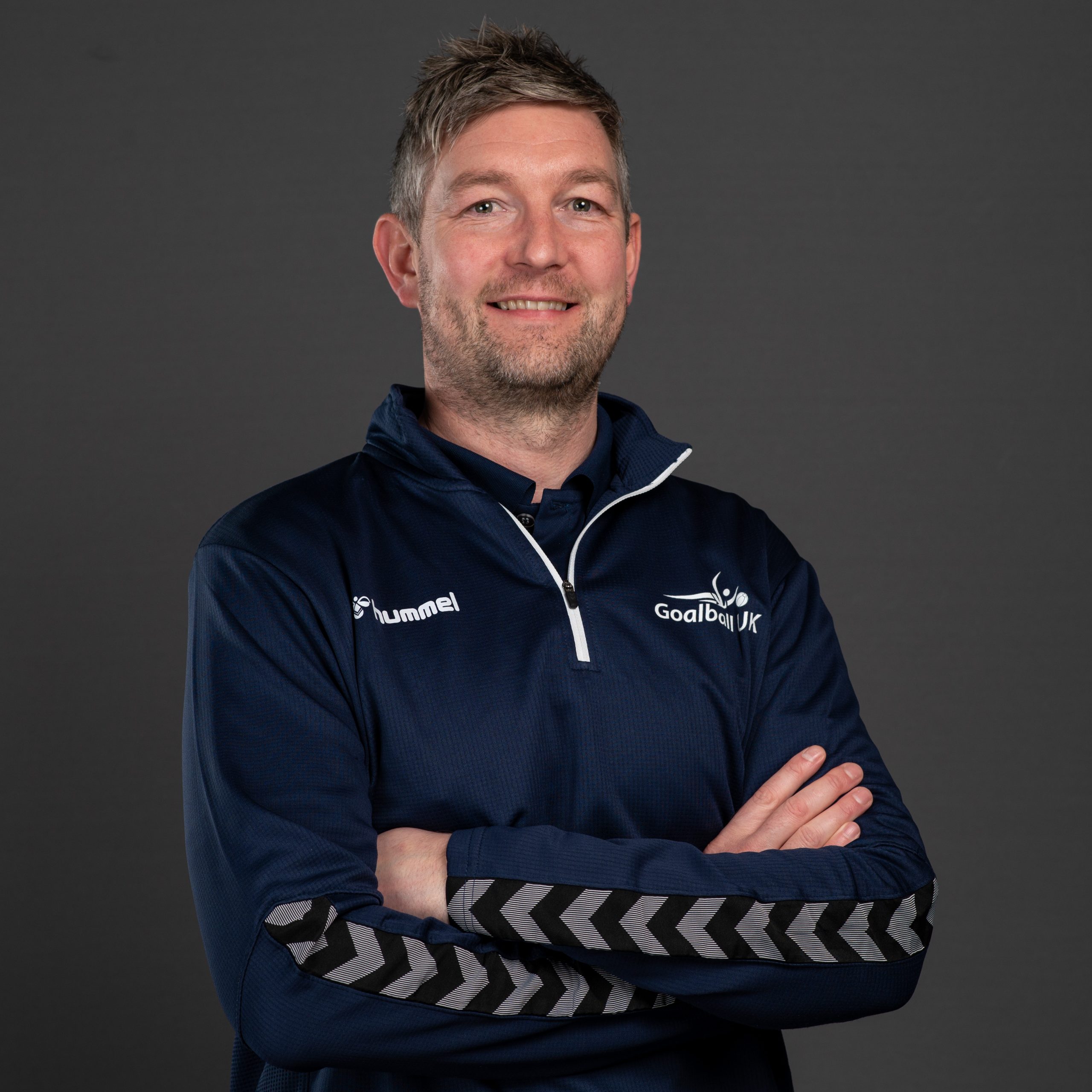 Gary Fraser Gary Fraser portrait. Gary is wearing a blue Goalball UK t-shirt and is stood in front of a white wall